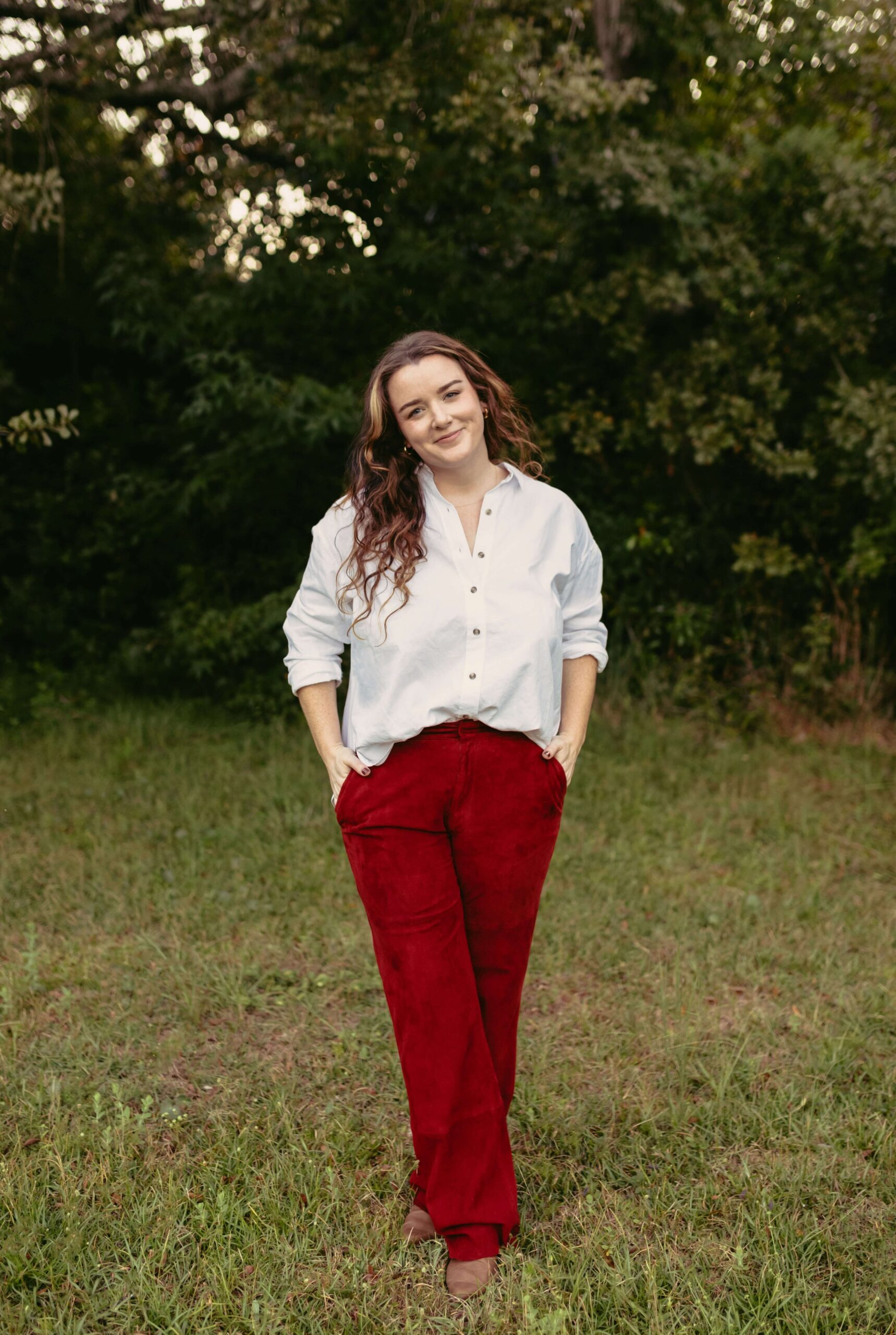 Photographer Brittney Stanley of Be Seen Photos poses wearing white button up & red pants in Panama City Florida