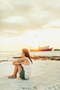 Empowering portrait of brunette young woman sitting on Cape San Blas beach, looking at horizon - taken by Brittney Stanley of Be Seen Photos