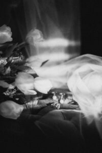 B&W Film shot of veil, rings & bridal bouquet on vintage chair in panama city beach florida