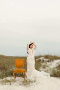 Bride posing regally velvet chair - on sand path in West PCB, Florida - wearing gown & holding flowers