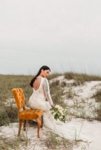 Bride posing regally velvet chair - on sand path in West PCB, Florida - wearing gown & holding flowers
